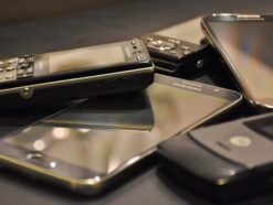 Some old cell phones and smartphones are on a table