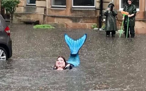 A woman dressed as a mermaid is photographed in the middle of the floods in Scotland.  World